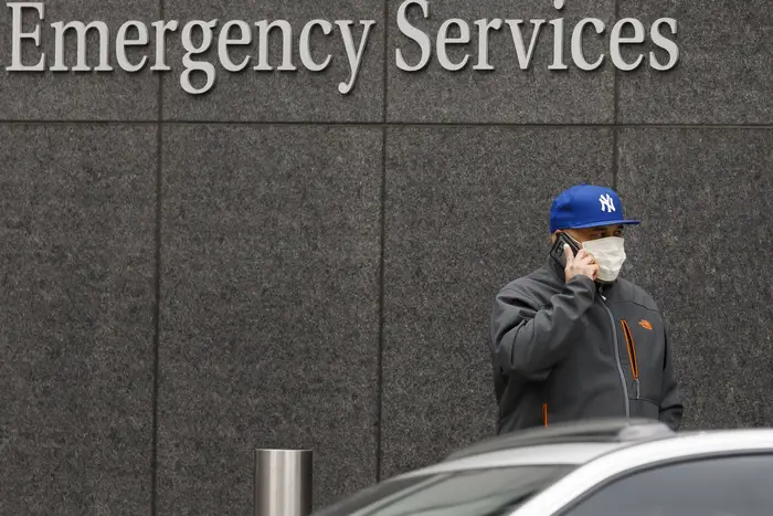 A man in a protective mask walks past a sign near the entrance to the emergency room at the NYU Langone Health Center hospital on Monday.